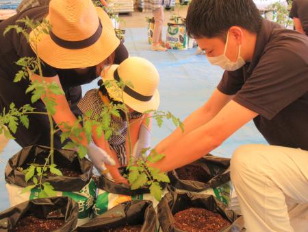 ＪＡ職員（右）から苗袋への定植について教わる参加者